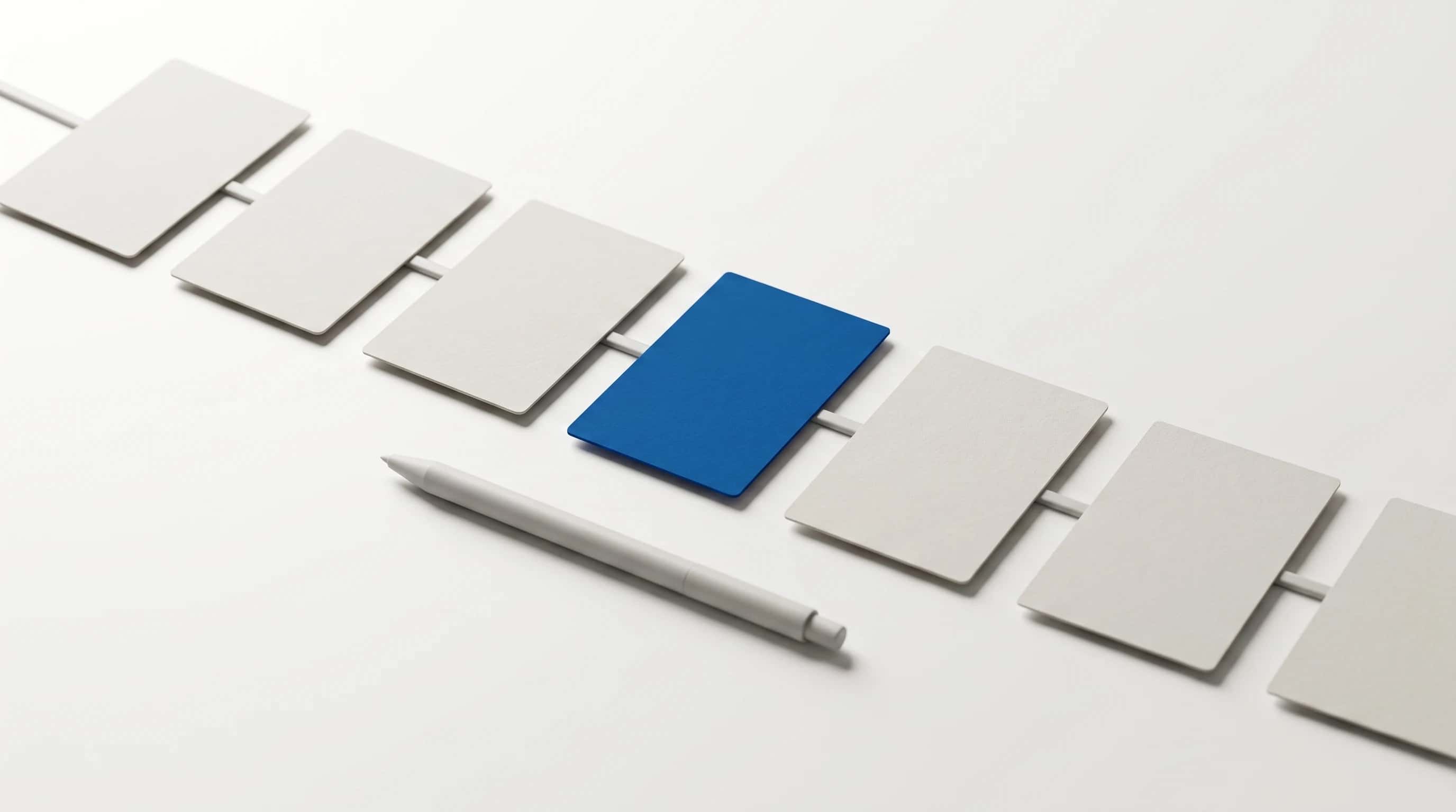 Zeven blanco kaarten op een rij verbonden door een dun lijntje, de vierde kaart in blauw, pen ernaast