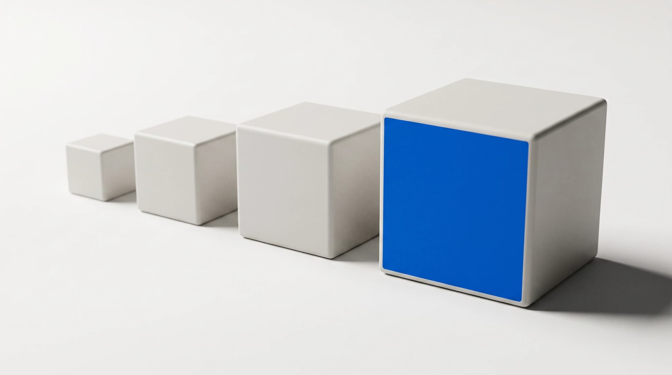 Vier matte kubussen in oplopende grootte op een rij, de grootste met één blauw vlak