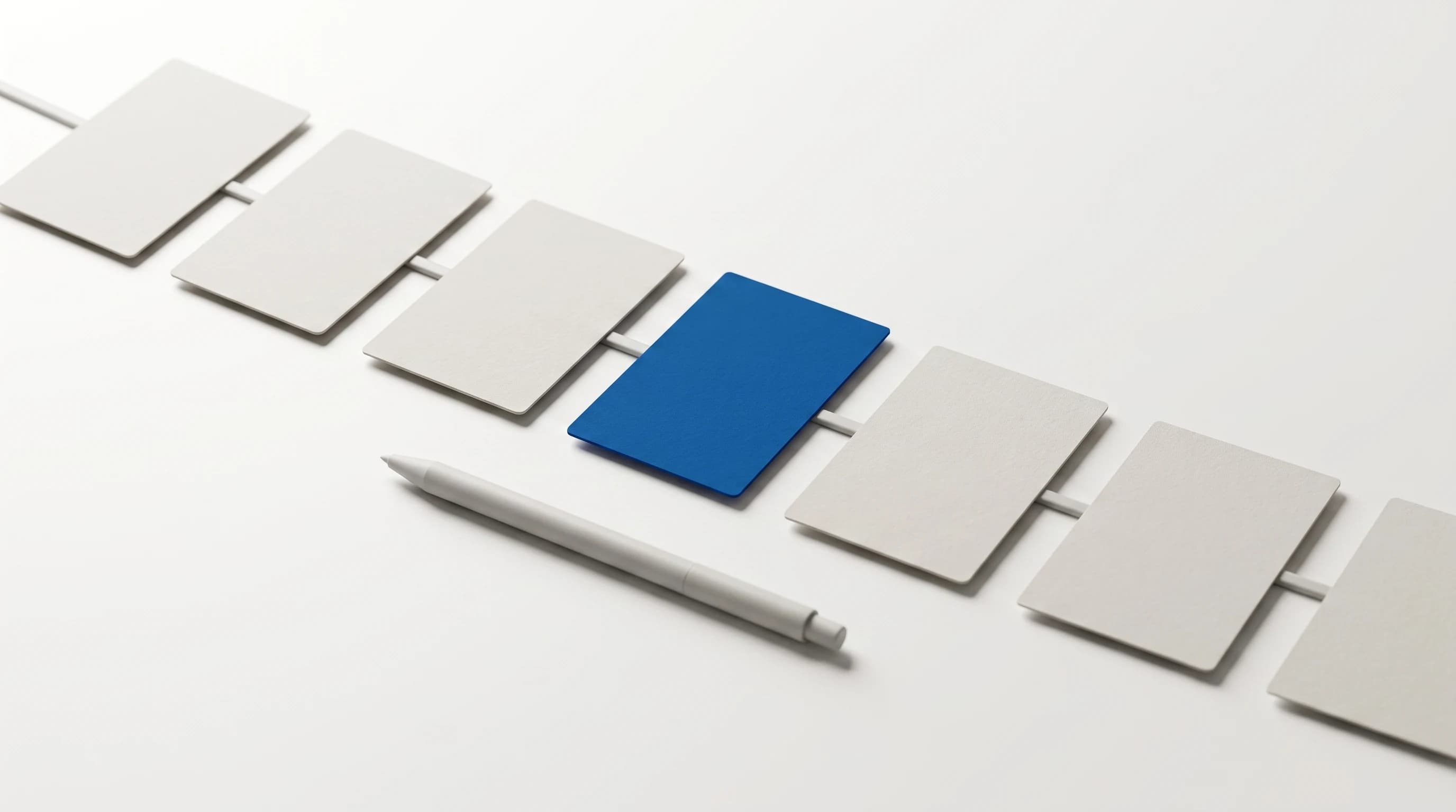 Zeven blanco kaarten op een rij verbonden door een dun lijntje, de vierde kaart in blauw, pen ernaast
