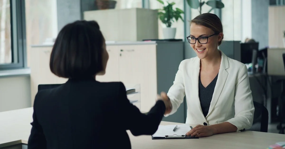 Twee vrouwen schudden elkaar de hand tijdens een sollicitatiegesprek op kantoor - HR recruitment en onboarding proces