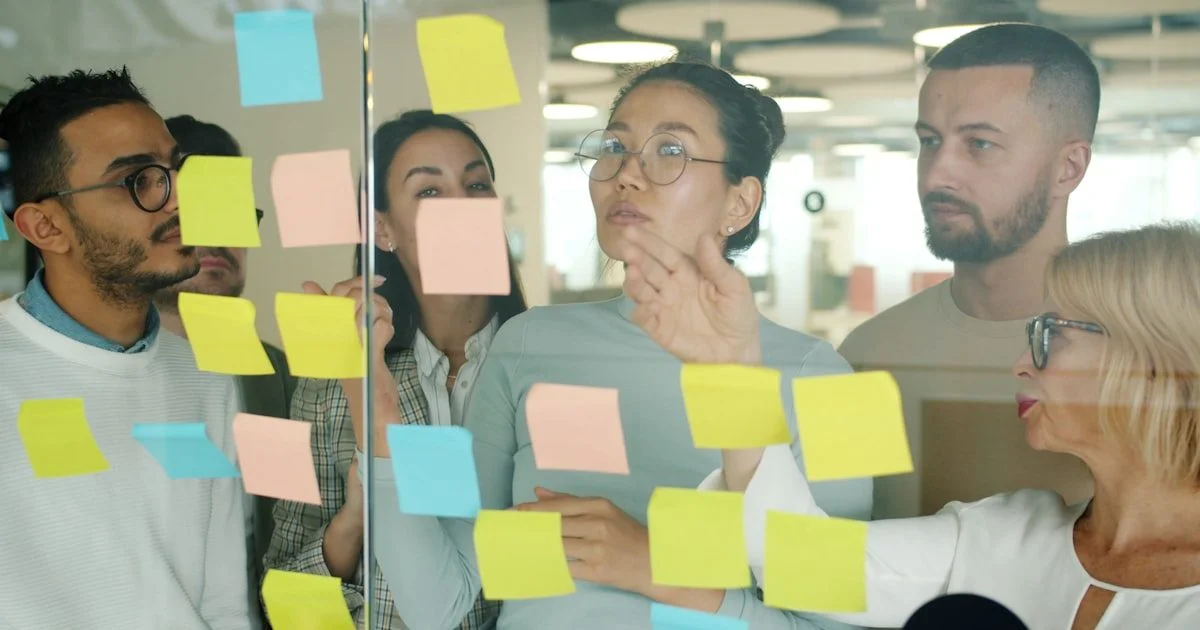 Jong creatief team werkt samen met sticky notes op kantoor - productieve teamvergadering en samenwerking