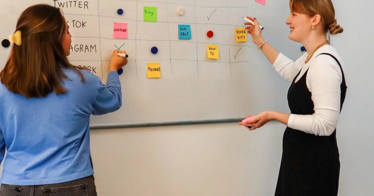 Twee vrouwen plannen content strategie bij een whiteboard met sticky notes — marketing team workflow en planning
