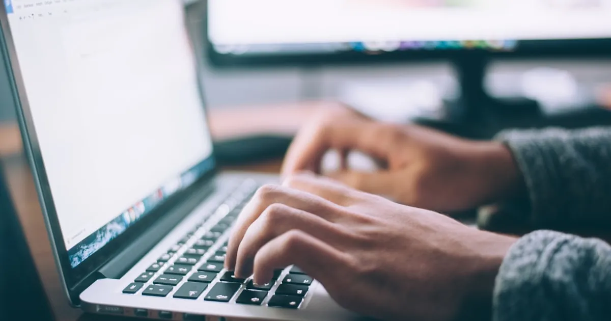 Webdesigner die aan een website bouwt achter een laptop in een kantooromgeving