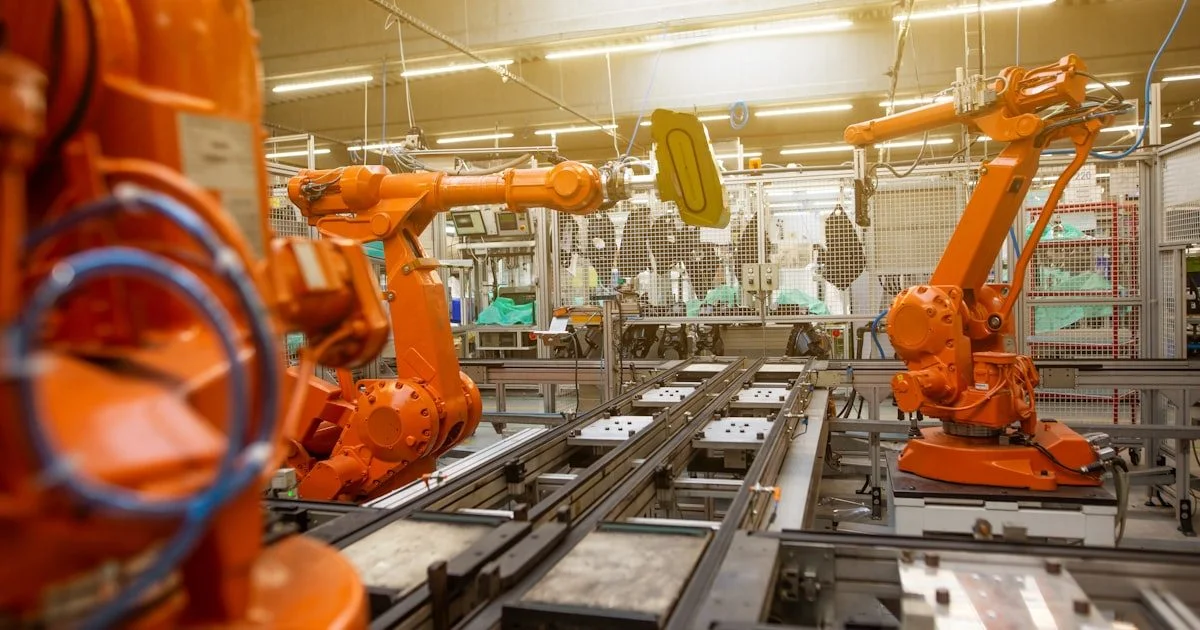 Fabriekshal met oranje industriele robots op een productielijn — symbool voor RPA en geautomatiseerde workflows