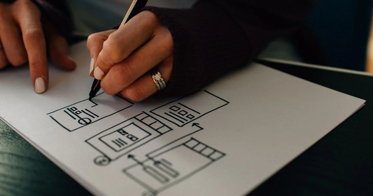 UX-designer tekent wireframes op papier voor een websiteontwerp — symbool voor het planningsproces en de kosten van website laten maken