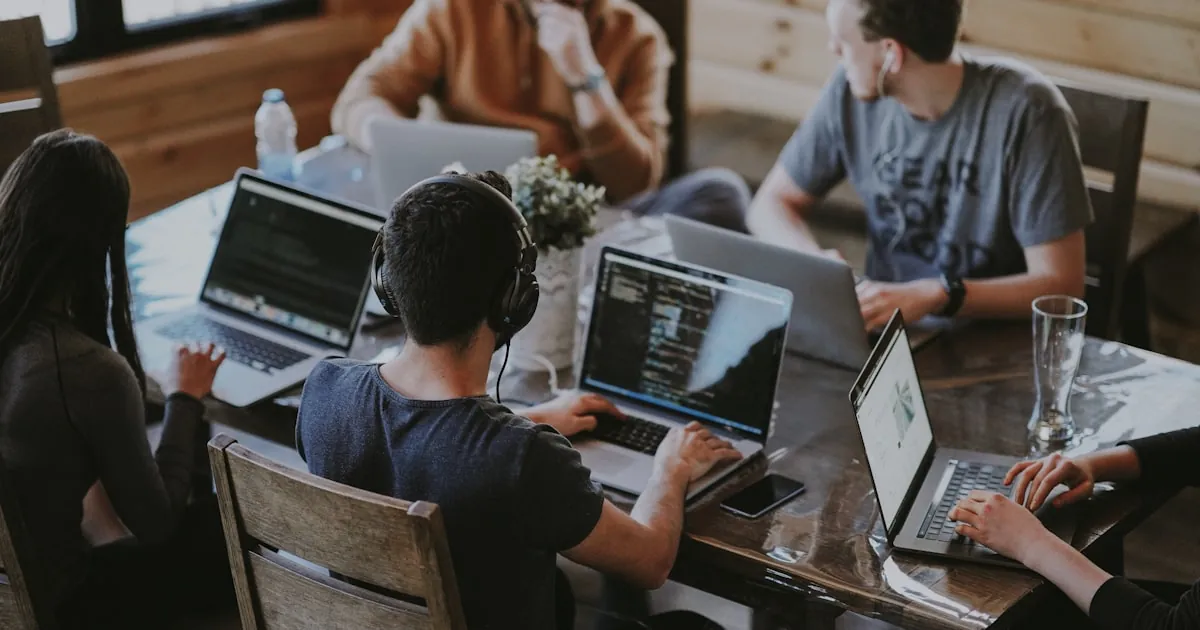 Drie mensen die samen om een laptop heen zitten en aan een websiteontwerp werken